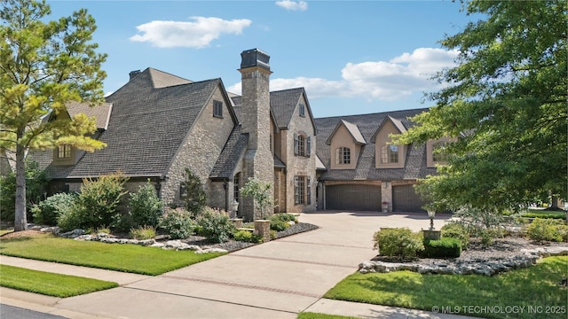 view of front of property featuring stone siding, driveway, and an attached garage