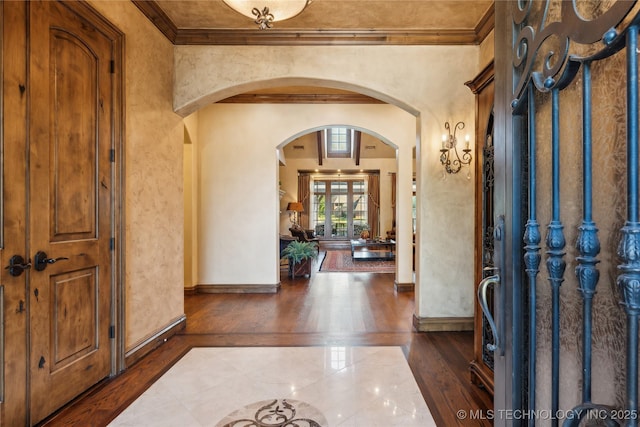 foyer with ornamental molding, arched walkways, and baseboards