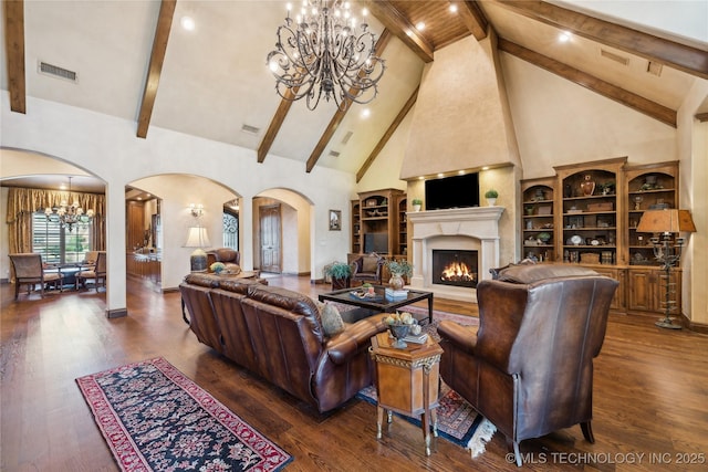 living area featuring arched walkways, wood finished floors, visible vents, and an inviting chandelier