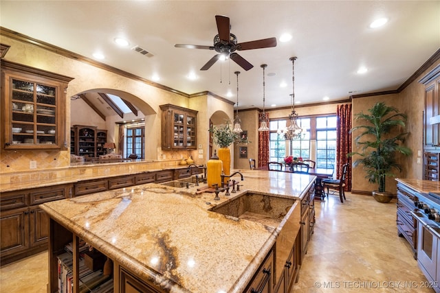 kitchen with range with two ovens, arched walkways, visible vents, glass insert cabinets, and light stone countertops