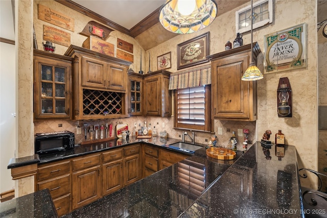 kitchen with a toaster, brown cabinets, decorative backsplash, glass insert cabinets, and a sink