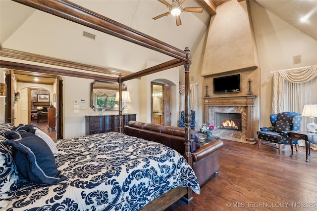 bedroom featuring arched walkways, a premium fireplace, wood finished floors, visible vents, and ornamental molding