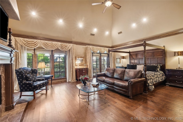 living room with a towering ceiling, visible vents, and wood finished floors