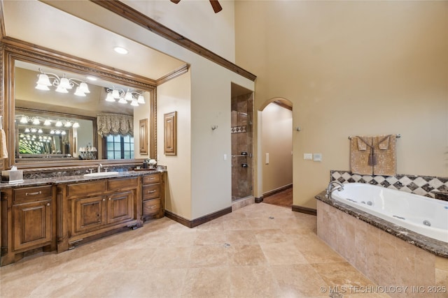 bathroom with baseboards, ceiling fan, a whirlpool tub, a tile shower, and vanity