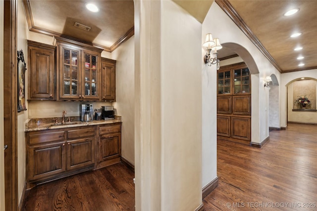 bar with arched walkways, dark wood finished floors, visible vents, and a sink