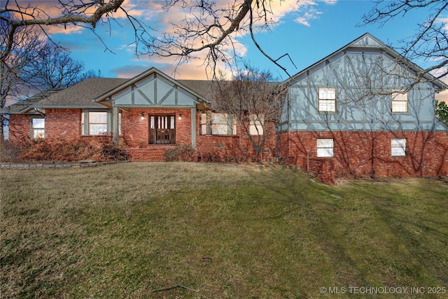 view of front of house featuring brick siding and a lawn