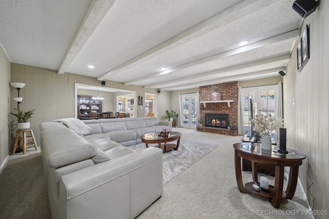 carpeted living room with beam ceiling, a brick fireplace, and a textured ceiling