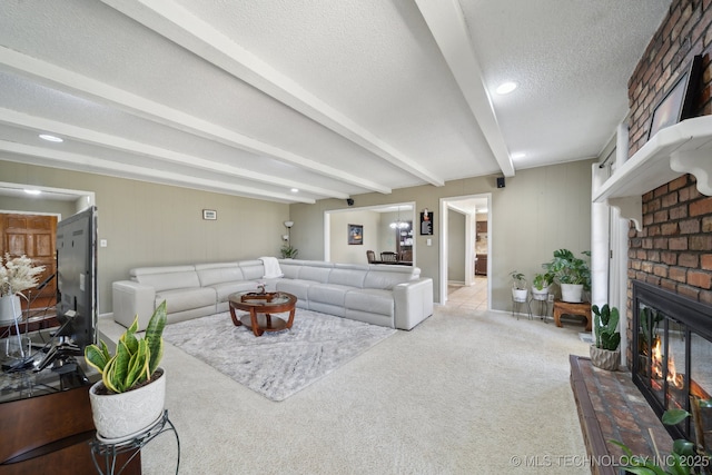 carpeted living area with beamed ceiling, a textured ceiling, and a brick fireplace