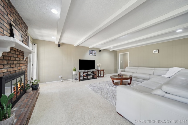 living area featuring beam ceiling, a brick fireplace, carpet, and a textured ceiling