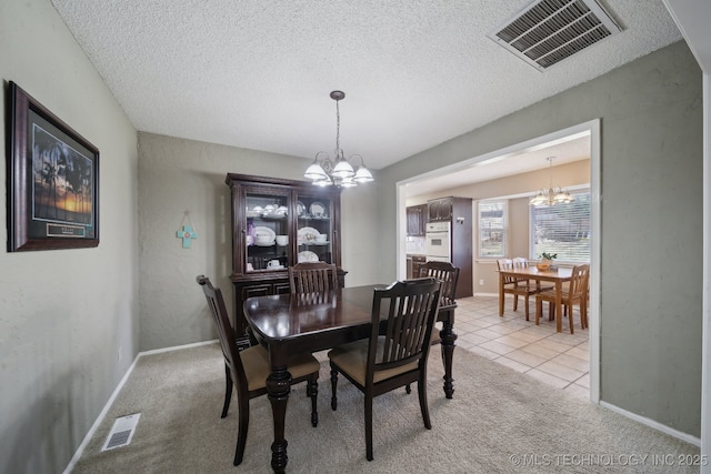 dining space featuring a chandelier, visible vents, light colored carpet, and a textured ceiling