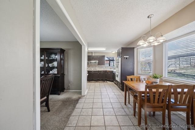 dining space featuring light tile patterned floors, light colored carpet, a notable chandelier, and a textured ceiling