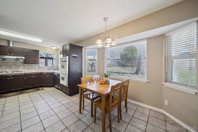 dining space featuring a notable chandelier, light tile patterned flooring, baseboards, and a textured ceiling