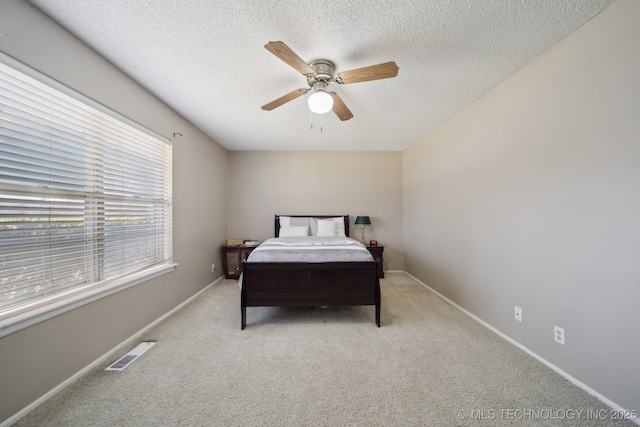 bedroom featuring light colored carpet, baseboards, visible vents, and a textured ceiling