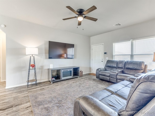 living room with visible vents, ceiling fan, baseboards, and wood finished floors