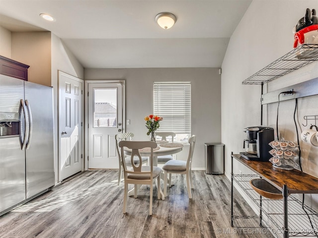 dining room featuring lofted ceiling, plenty of natural light, and wood finished floors