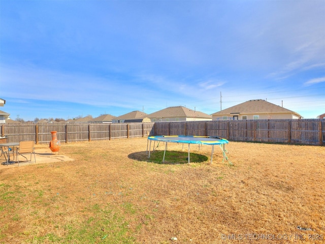 view of yard with a trampoline, a patio area, and a fenced backyard