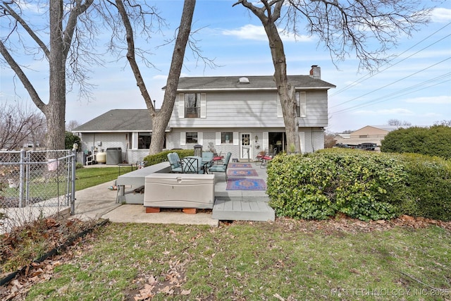 back of house featuring central AC, brick siding, fence, a gate, and a chimney