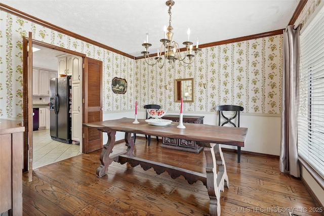 dining space with crown molding, light wood-style flooring, wainscoting, a textured ceiling, and wallpapered walls