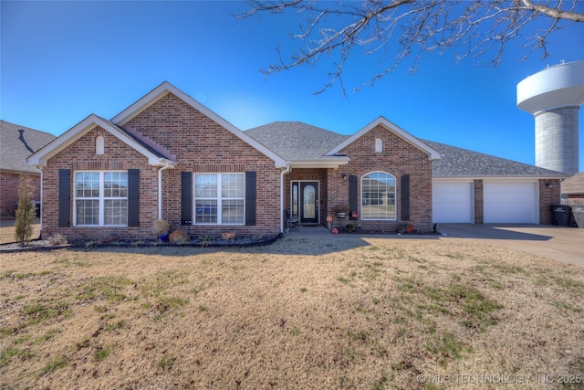 single story home with concrete driveway, brick siding, an attached garage, and a front yard