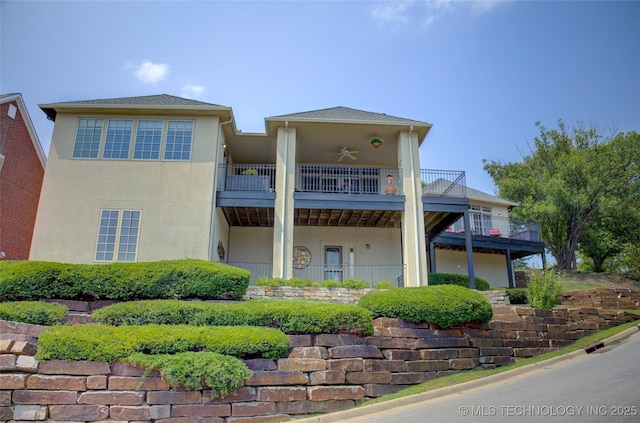 rear view of house with a balcony, stucco siding, and a ceiling fan