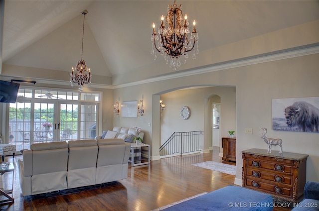 living area with baseboards, wood finished floors, arched walkways, a notable chandelier, and high vaulted ceiling