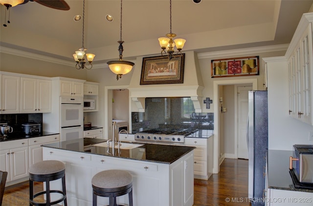 kitchen with a raised ceiling, white appliances, dark wood finished floors, and white cabinets