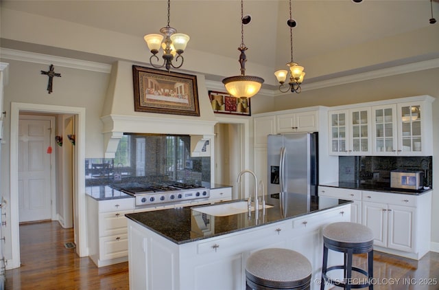 kitchen featuring dark wood finished floors, a sink, glass insert cabinets, appliances with stainless steel finishes, and a notable chandelier