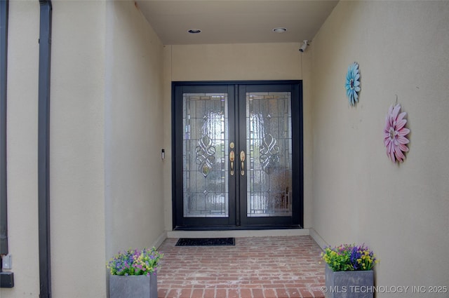 property entrance featuring stucco siding and french doors