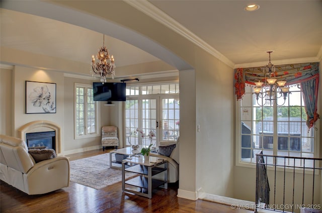 living room featuring dark wood-style floors, plenty of natural light, a chandelier, and crown molding