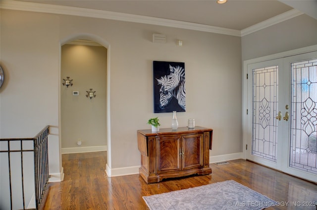 entryway with ornamental molding, wood finished floors, french doors, arched walkways, and baseboards