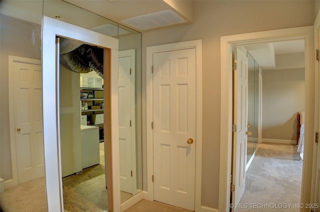 hallway with light colored carpet, baseboards, and visible vents