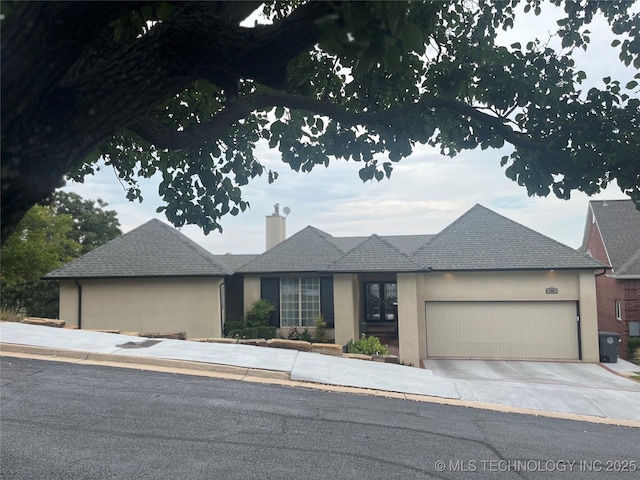 view of front of property featuring stucco siding, a garage, and a chimney