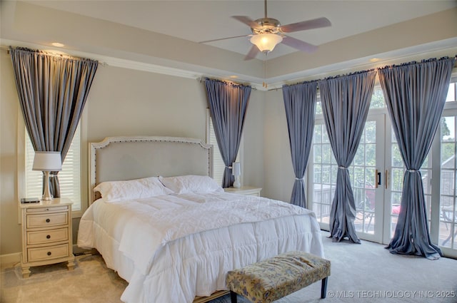 bedroom featuring ceiling fan, light carpet, a raised ceiling, and access to exterior