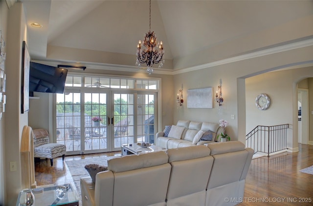 living room with high vaulted ceiling, wood finished floors, french doors, arched walkways, and an inviting chandelier