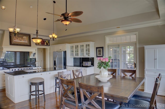 dining space featuring dark wood finished floors, a raised ceiling, and a ceiling fan