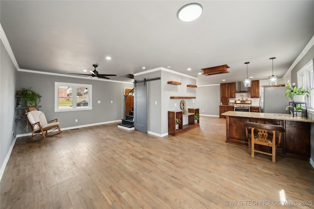 kitchen with crown molding, open shelves, stainless steel appliances, a barn door, and wall chimney exhaust hood