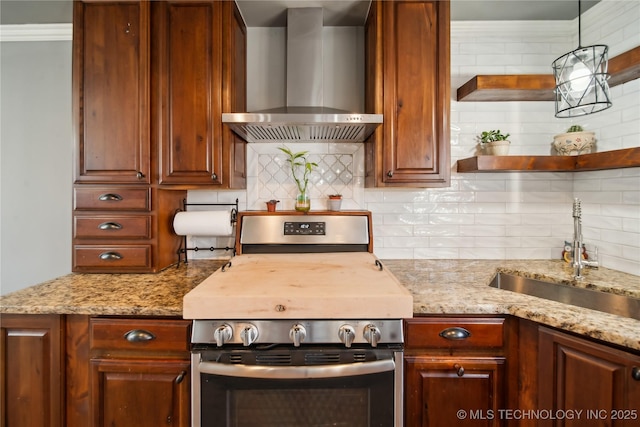 kitchen featuring light stone counters, decorative backsplash, stainless steel gas stove, a sink, and wall chimney exhaust hood