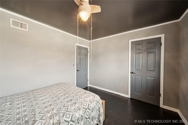 bedroom with baseboards, visible vents, wood finished floors, and ornamental molding