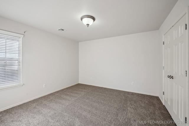 carpeted spare room with visible vents and baseboards