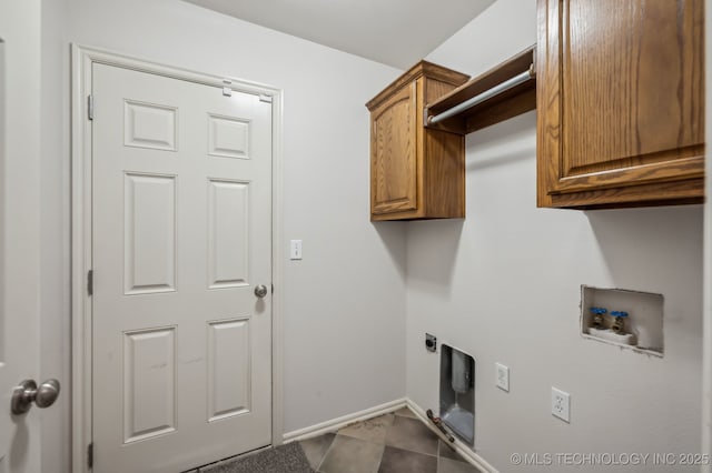 laundry area featuring dark tile patterned floors, washer hookup, baseboards, cabinet space, and electric dryer hookup