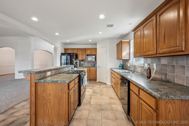 kitchen featuring black appliances, visible vents, brown cabinets, and a sink