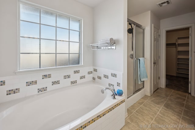 full bath with a garden tub, tile patterned flooring, visible vents, a shower stall, and a walk in closet