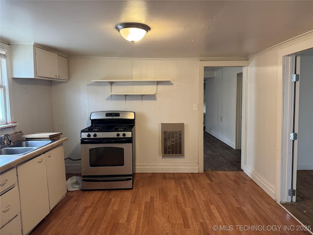 kitchen featuring a sink, white cabinetry, stainless steel range with gas stovetop, and wood finished floors