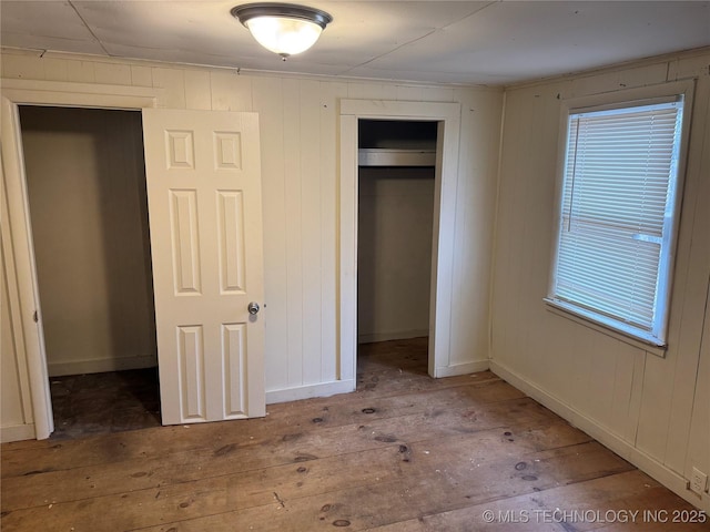 unfurnished bedroom featuring a closet, baseboards, and hardwood / wood-style flooring