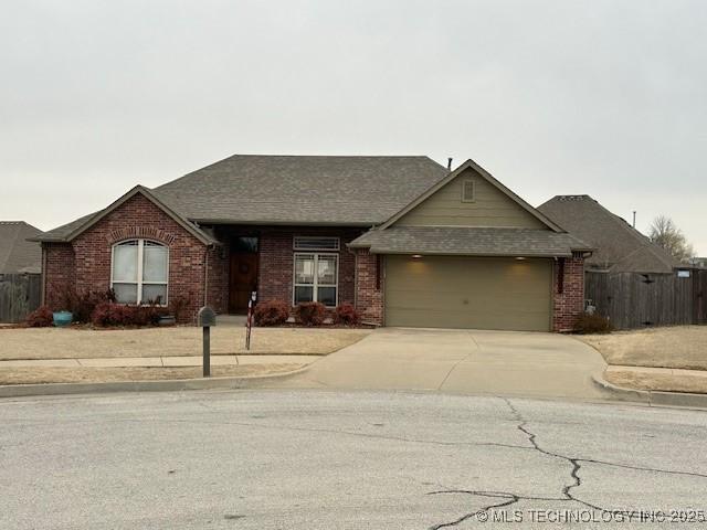 ranch-style home featuring a garage, concrete driveway, brick siding, and fence