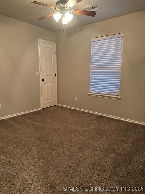 empty room featuring baseboards, visible vents, dark carpet, and a ceiling fan