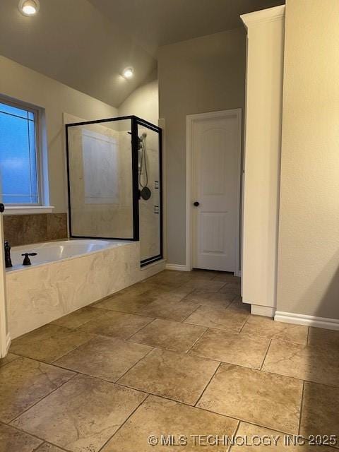 bathroom with vaulted ceiling, a stall shower, a garden tub, and baseboards