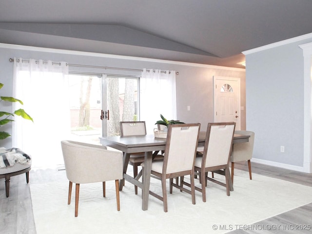 dining space with light wood-style floors, lofted ceiling, crown molding, and baseboards