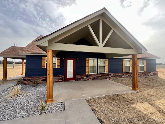 view of front of house with a shingled roof and brick siding