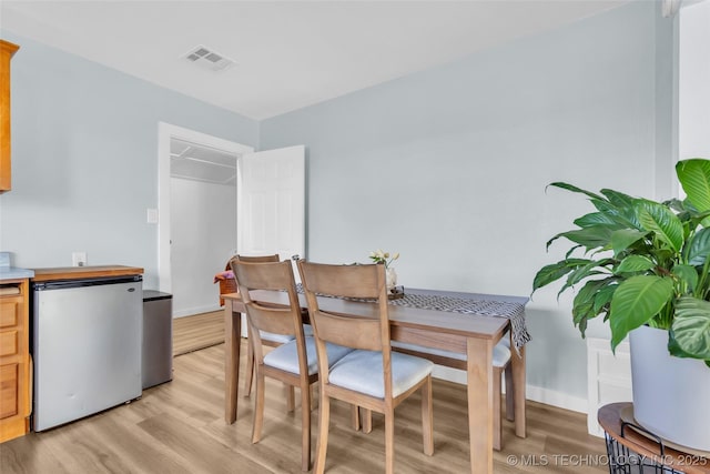 dining area with light wood finished floors, baseboards, and visible vents